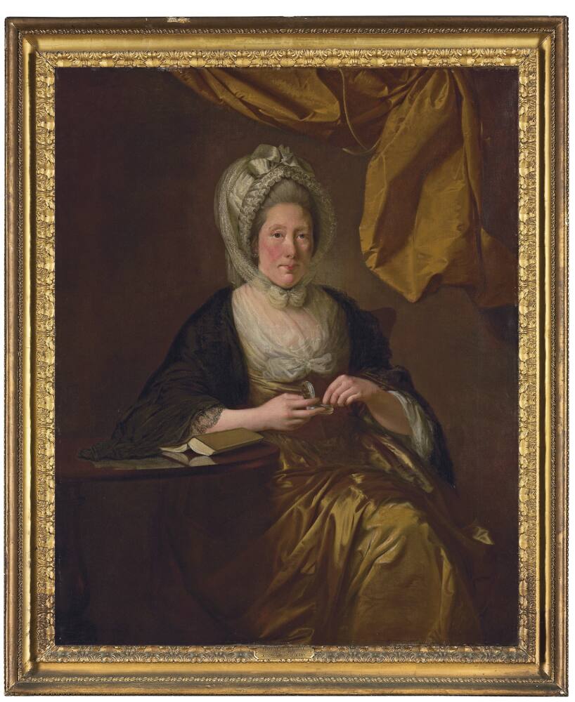 Portrait of a woman, called Mary Hurt; half-length, turned slightly to the right, eyes facing forward. She is seated beside a highly polished dark wood table upon which is an open, upturned book. She holds a small silver and tortoiseshell box in her hand into which her fingers reach as though to remove something from it. To the right-hand corner is an ochre yellow, silk drape. She wears a satin, ochre yellow gown with a back lace-trimmed cape over her shoulders. A sheer white kerchief is secured at her breast by a bow. Her hair is light grey and partly covered by an elaborate white cap decorated with pleats and a bow. A sheer white scarf is wrapped around this cap and tied beneath her chin. Painted by Joseph Wright of Derby (1734 - 1797). Oil on canvas in gilded frame.
