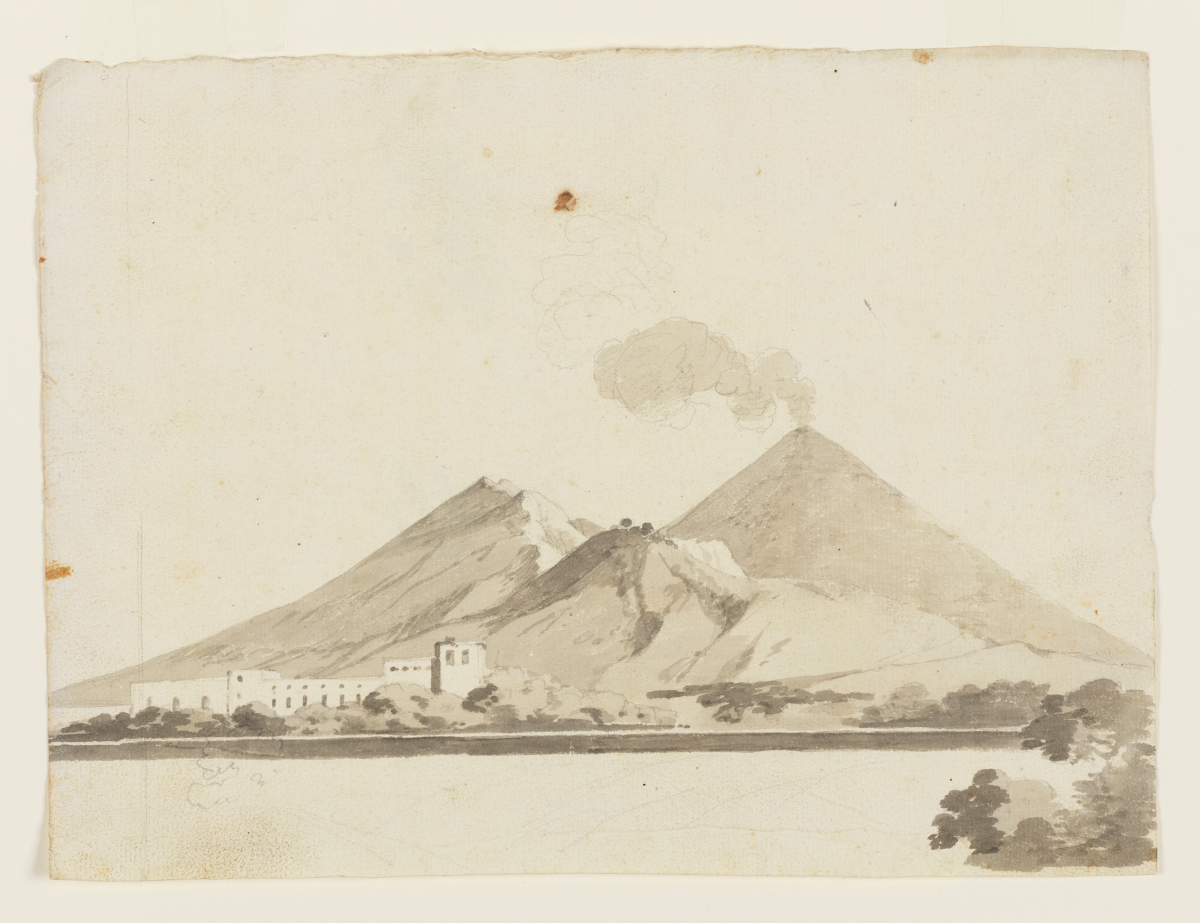 Drawing of a volcano, idenified as Vesuvius in Italy. Buildings in the foothills of the volcano and a slight cloud of smoke rising. Slight sketches of terrain and foliage in the foreground. Ruled pencil lines running vertically on the left. The verso contains faint foliage studies. Made by Joseph Wright of Derby (1734-1797), c. 1774-1775. Ink wash over pencil on laid paper. Displayed in a cream window mount.